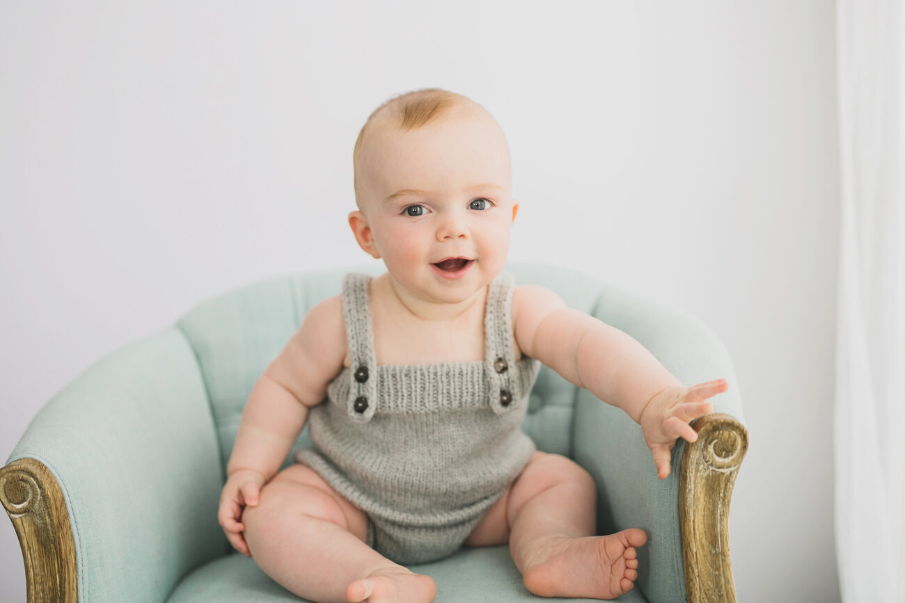 Happy baby boy in knit romper on vintage mint chair, Boise sitter session