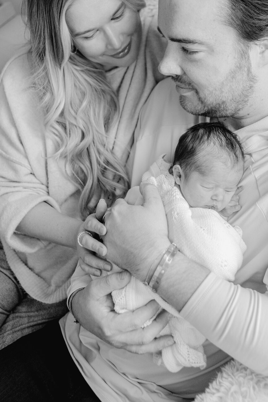 Mother and father cradling their swaddled newborn together, black and white family newborn session in Boise