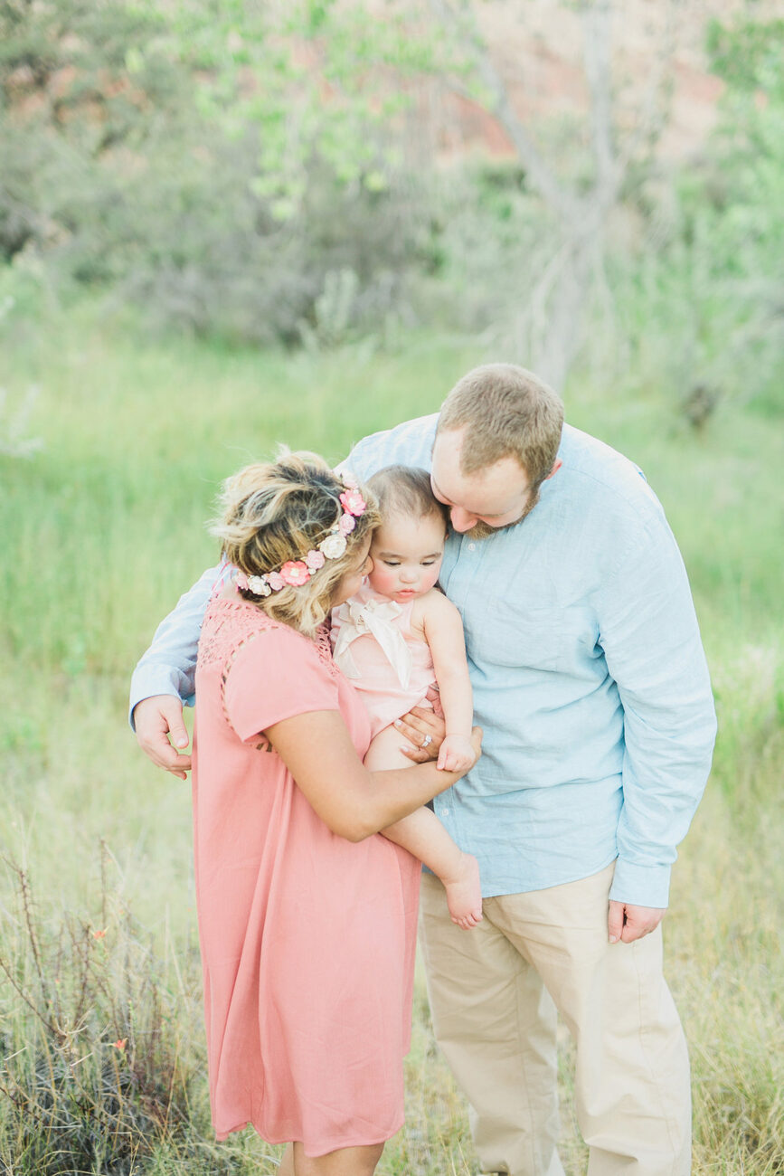 Family embracing in grassy field, mom in pink dress holding baby, Boise family photographer