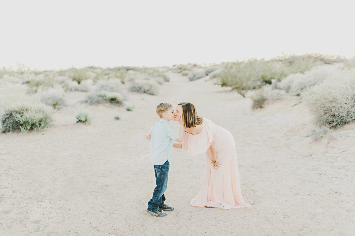 Mom in pink dress holding hands with young son in desert, Boise family photographer