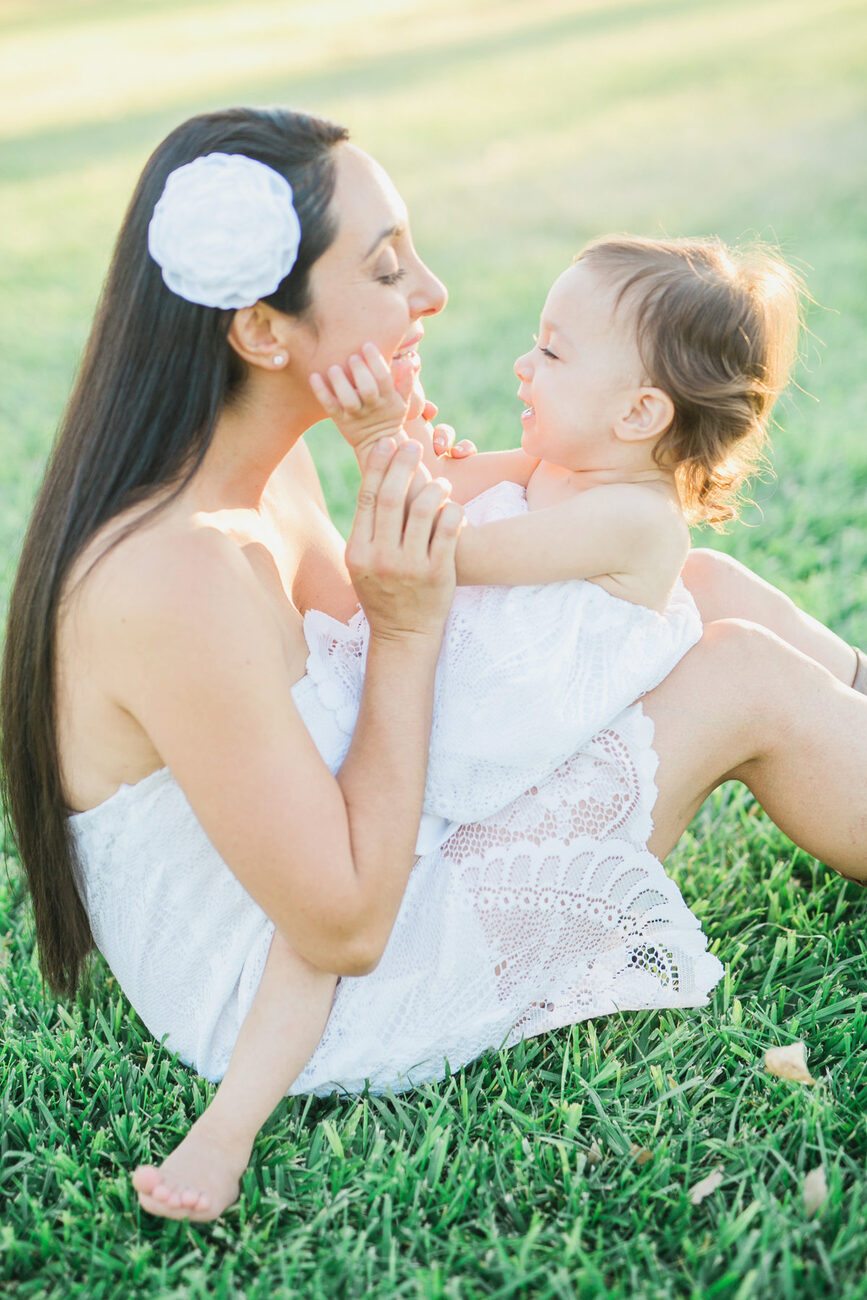 Mother laughing with toddler daughter on the grass, connection-driven family photography