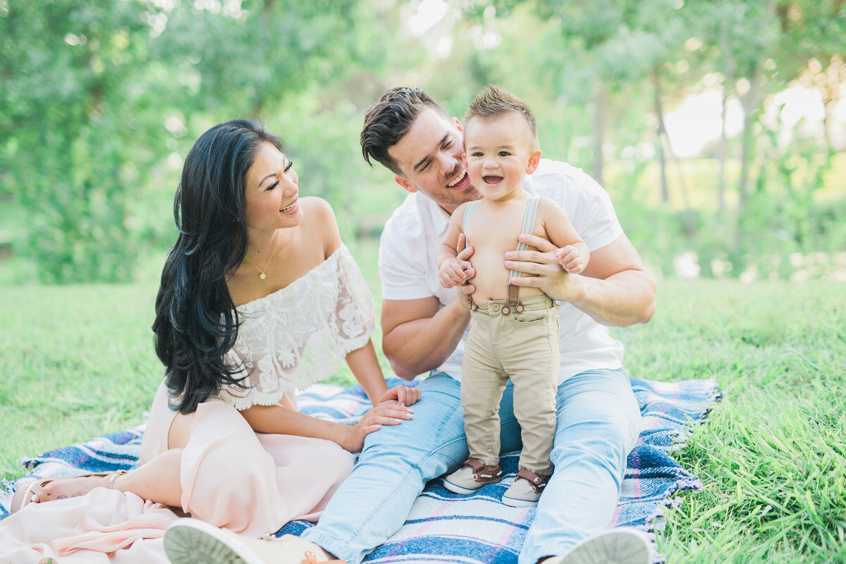 Parents laughing with baby boy on picnic blanket, on-location Boise family session