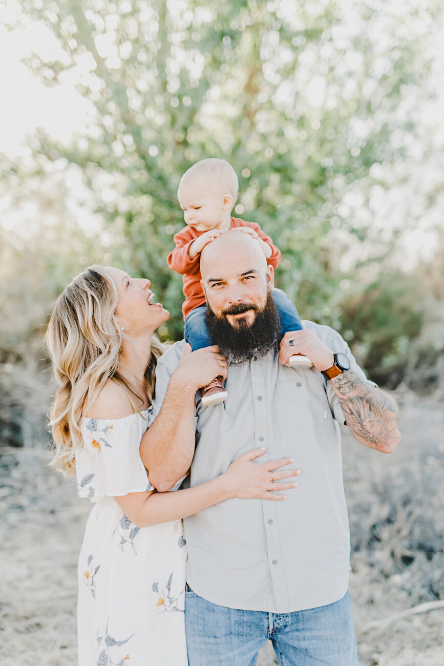 Baby riding on dad’s shoulders while mom smiles, playful Boise family photography