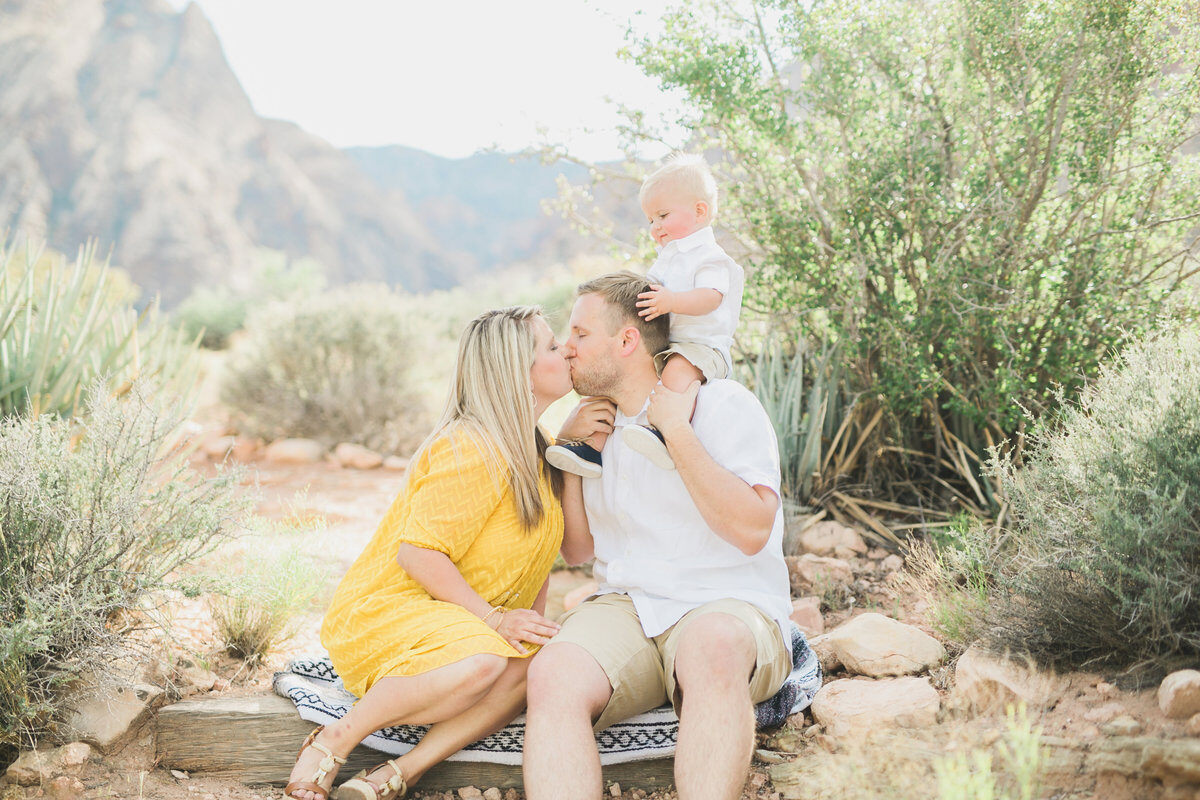 Couple kissing while holding baby during desert family session, Boise family photography
