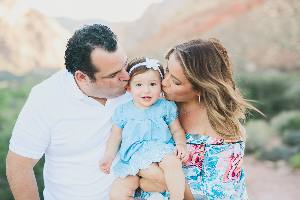 Parents kissing baby girl between them, outdoor Boise family photography