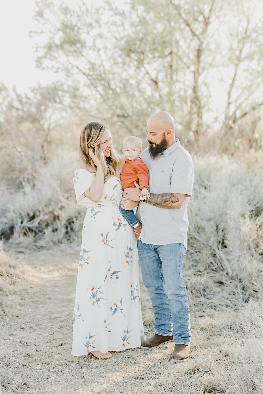 Couple embracing in desert brush, mom in floral dress, outdoor family session