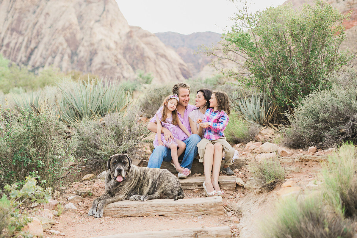 Family with their dog sitting among red rocks, adventurous Boise family photos