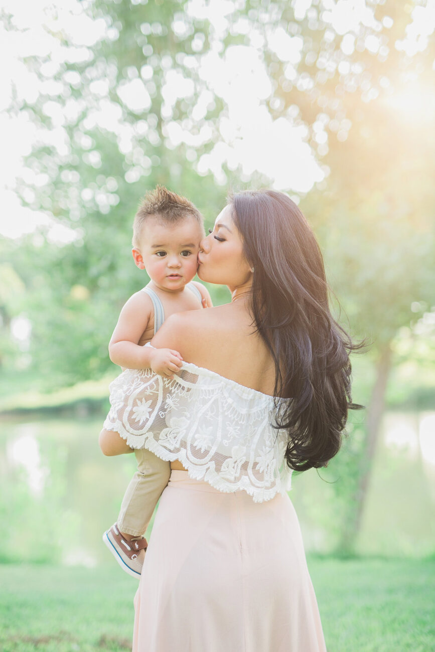 Mom kissing toddler daughter by the lake in golden light, Boise family photos