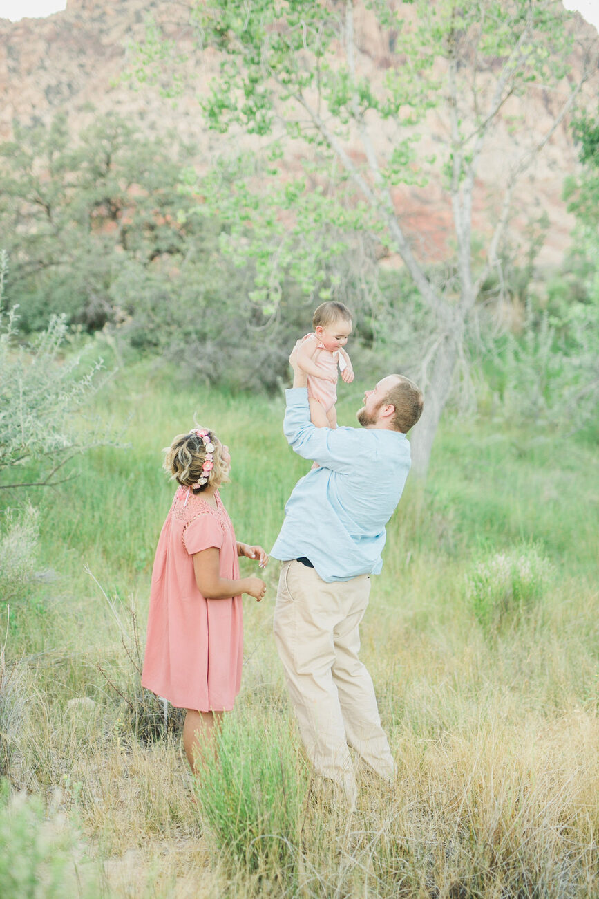 Parents playing with daughter in tall grass, on-location Boise family photos