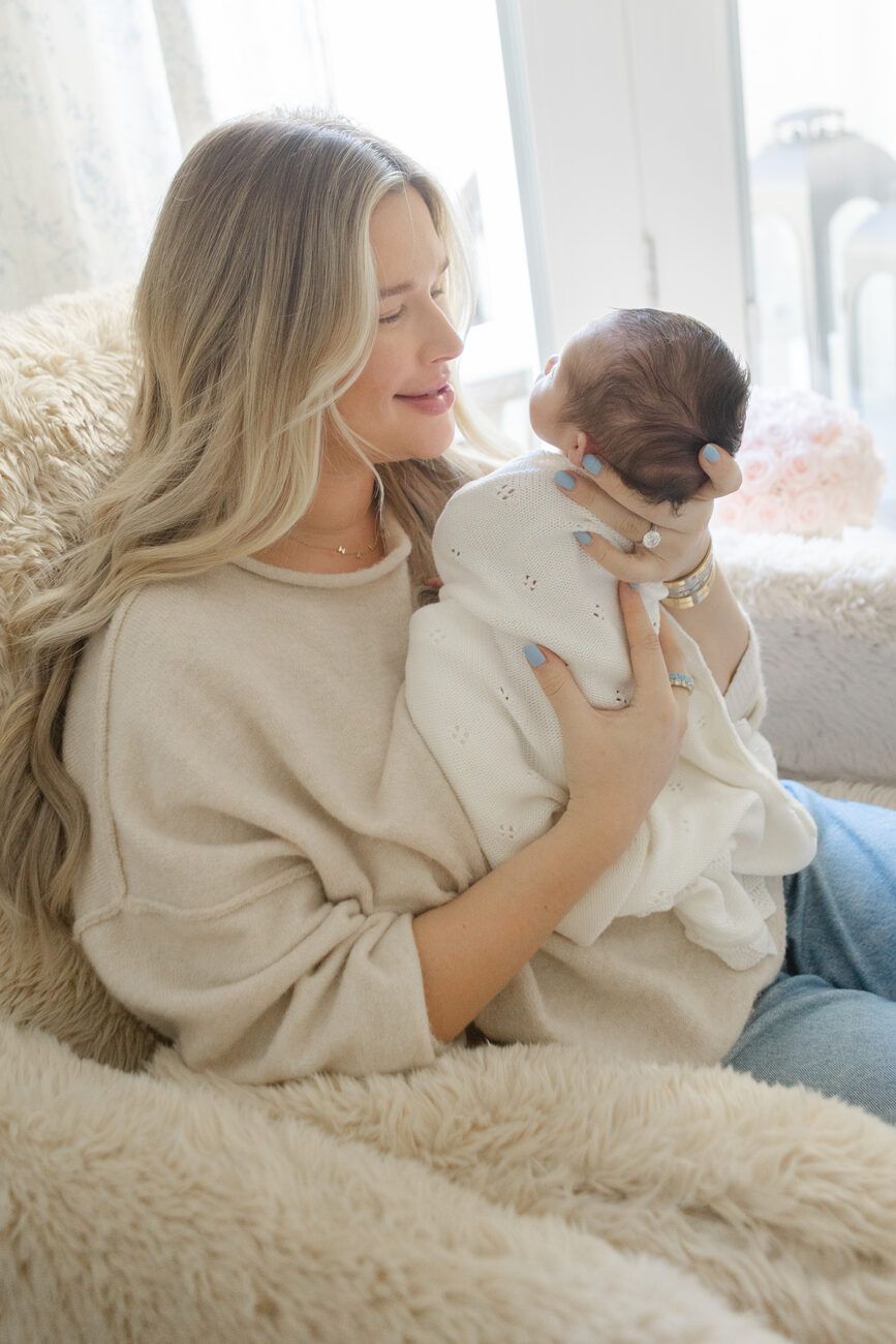 Mother holding her newborn in soft window light during an in-home newborn photographer session in Boise
