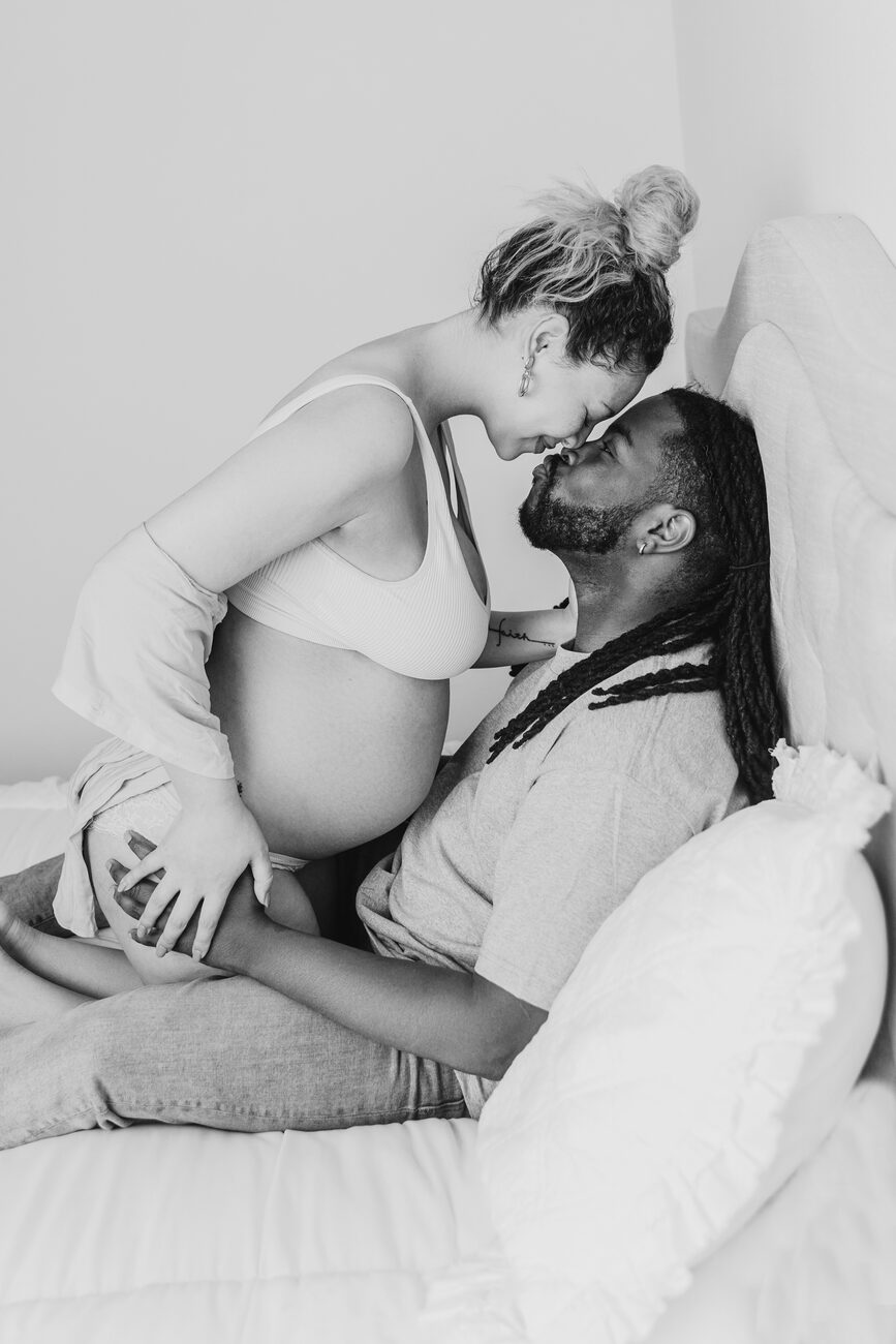 In-home maternity session in Boise, expecting couple touching foreheads on the bed