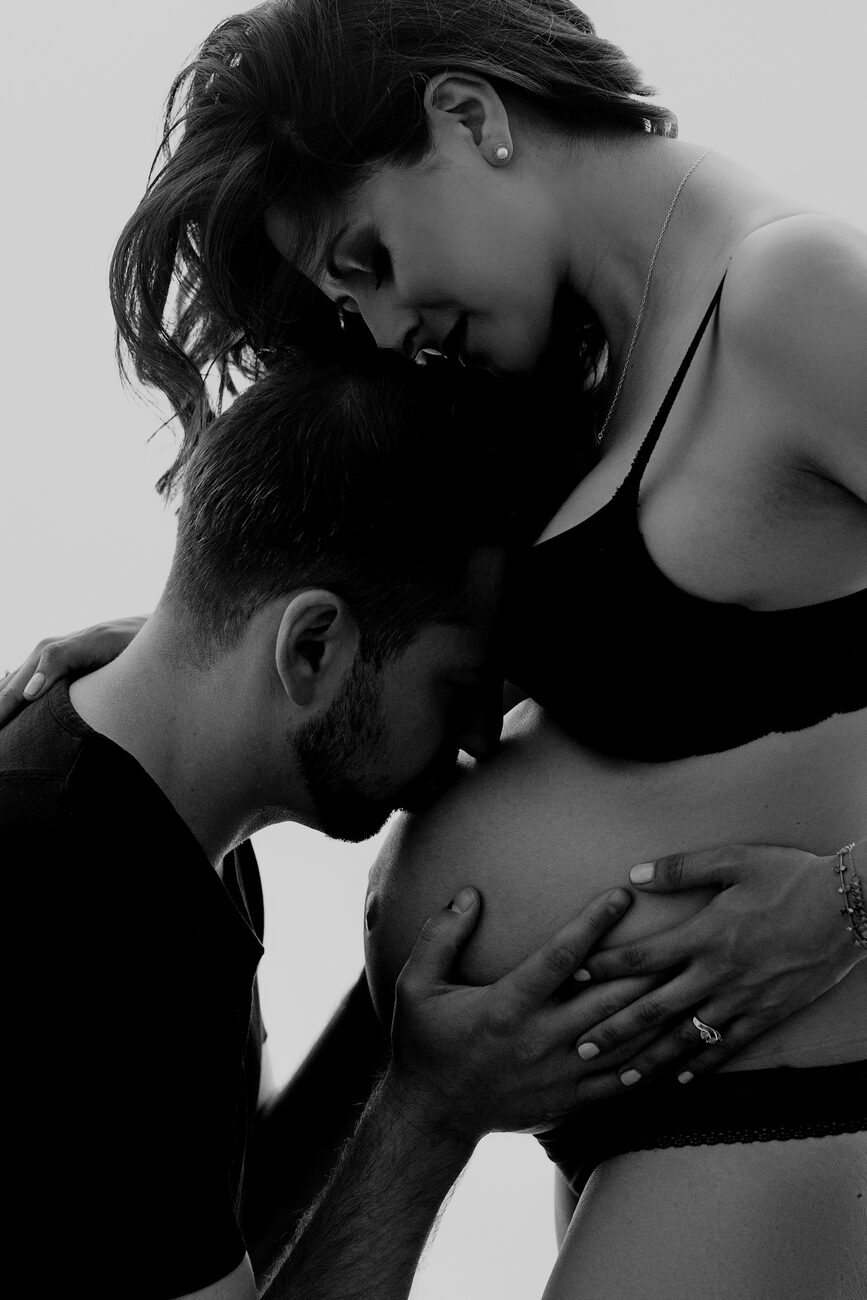 Father kissing pregnant belly, intimate black and white Boise maternity photography