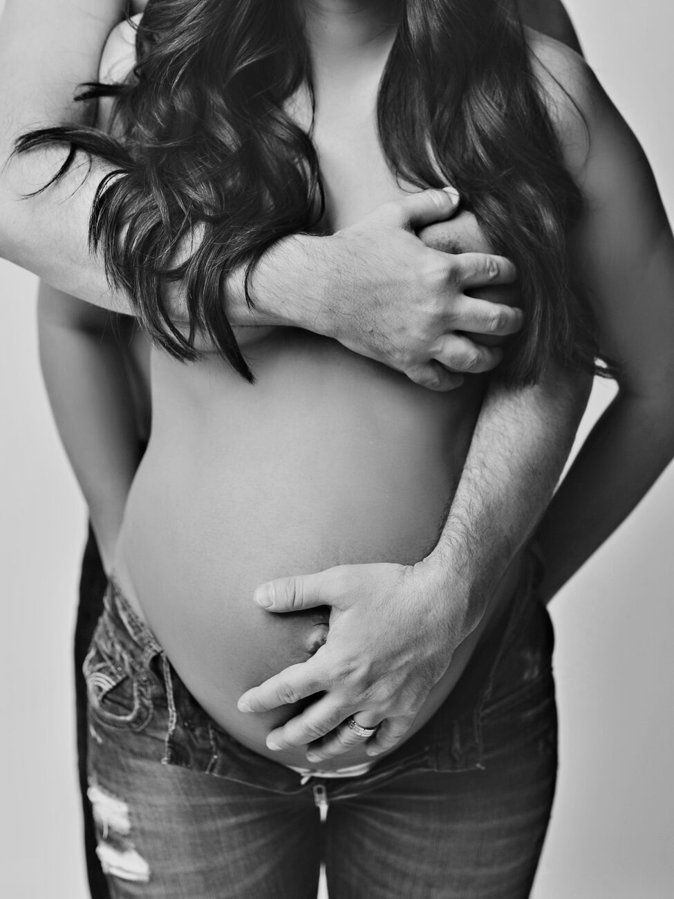 Black and white detail of couple’s hands on pregnant belly, Boise maternity photos