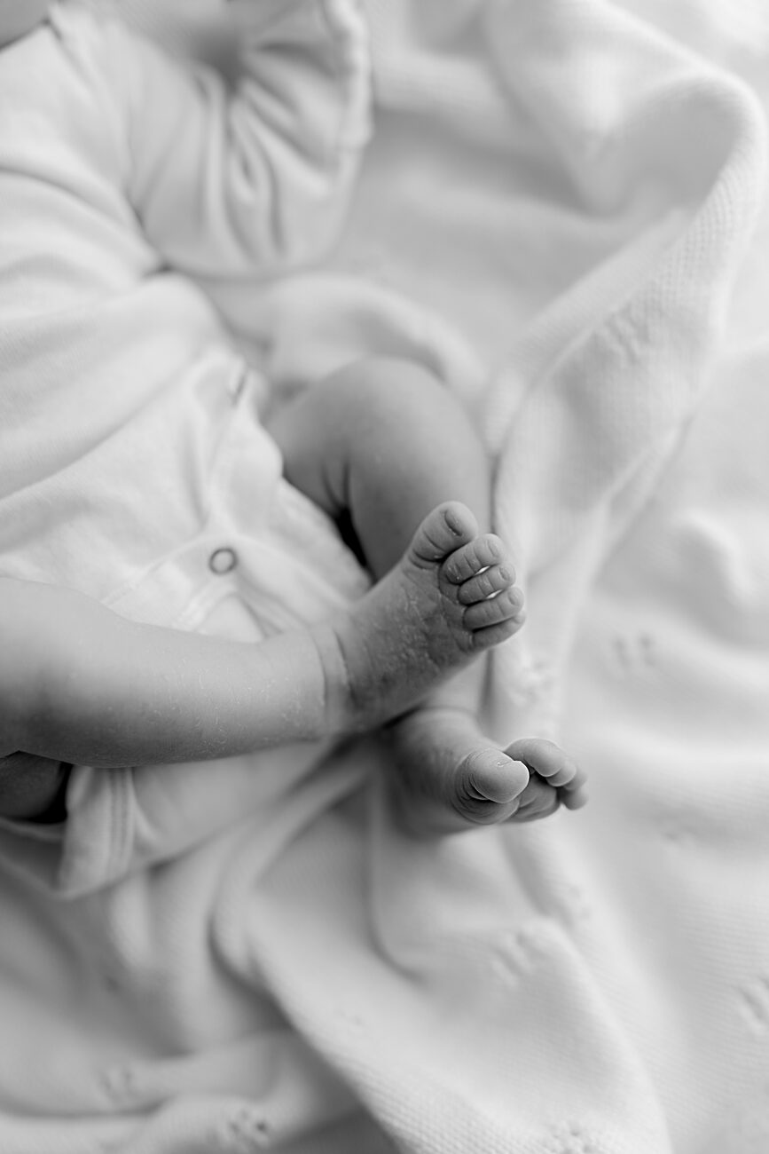 Newborn legs and feet on a white knit blanket, black and white detail by a Boise newborn photographer