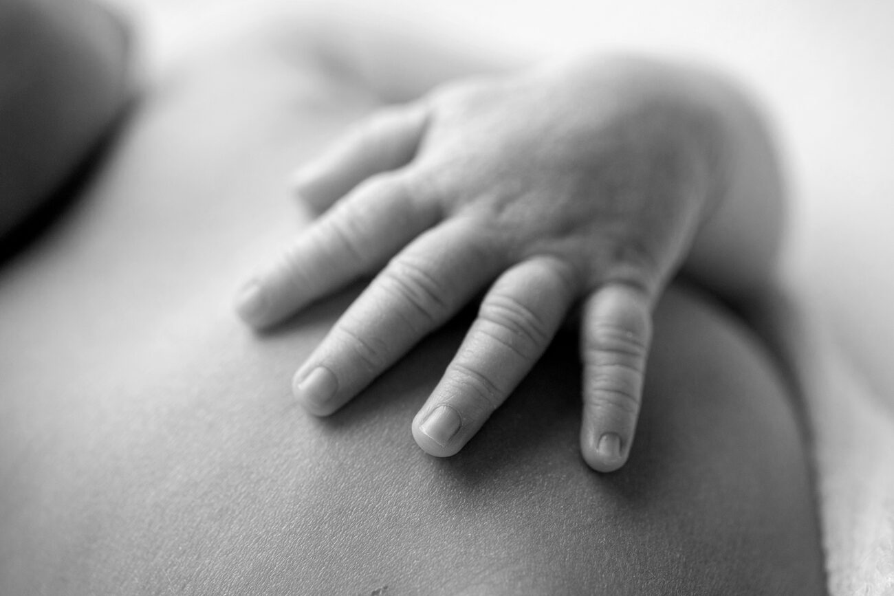 Macro black and white detail of a newborn’s hand resting on their back, Boise newborn photos