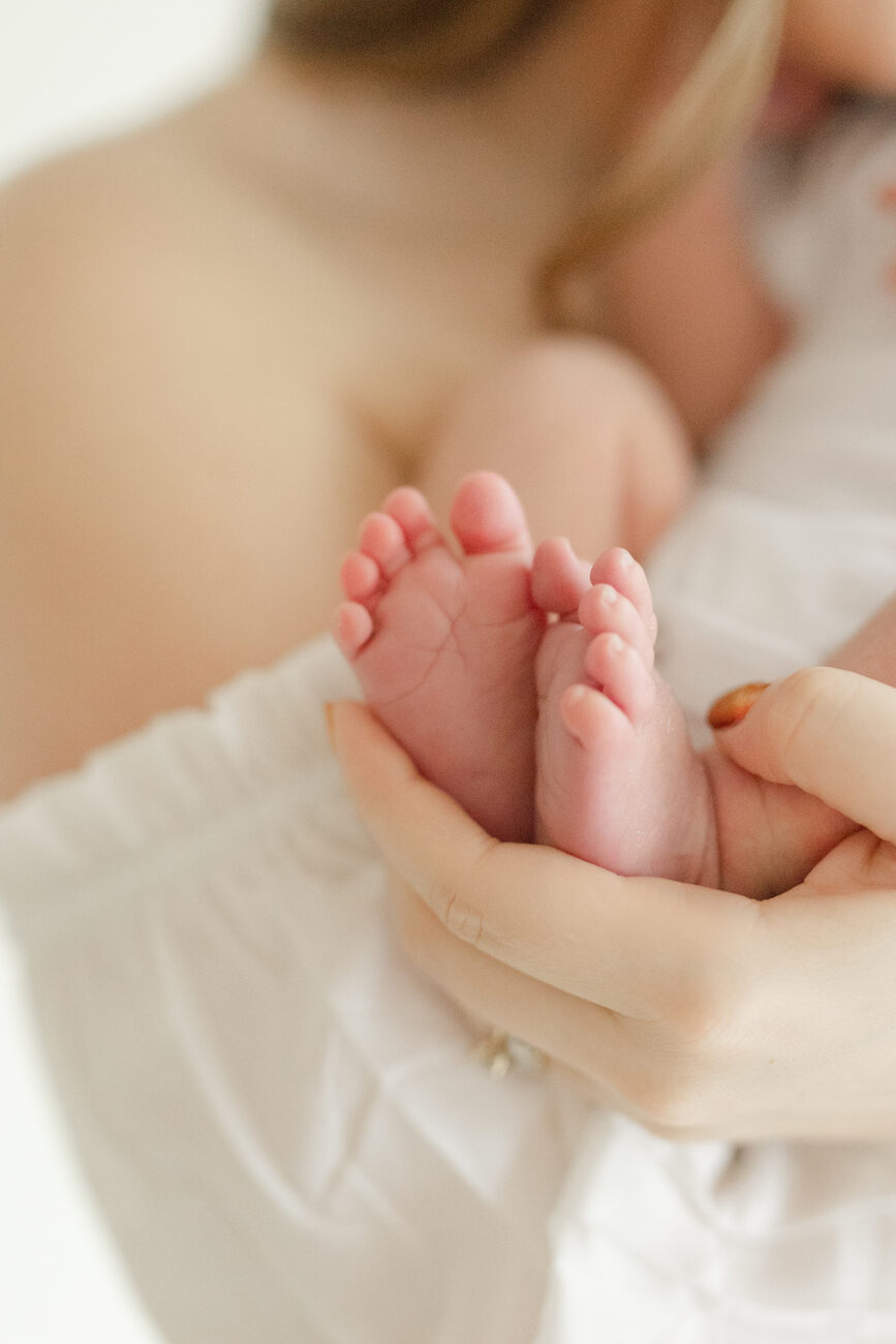 Tiny newborn feet cupped in a mother’s hands, soft natural light Boise newborn photos