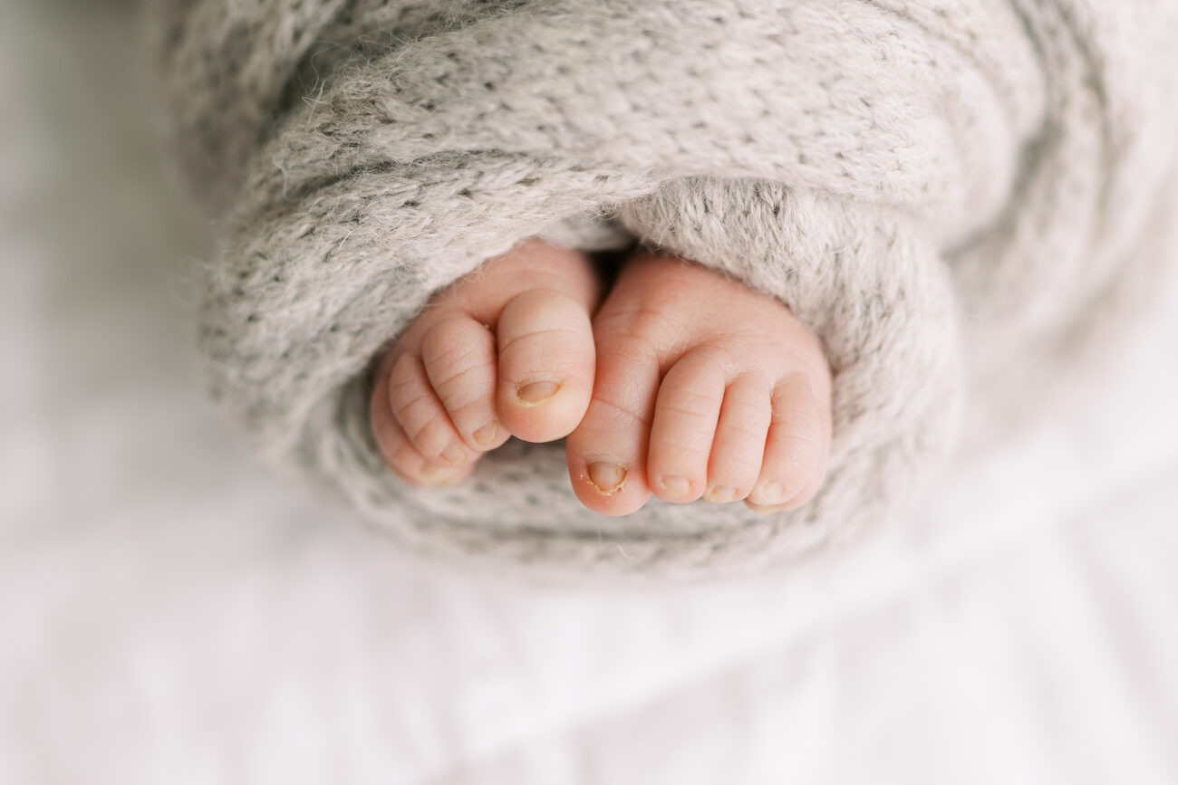 Tiny newborn toes peeking out of a gray knit blanket, Boise newborn photography detail